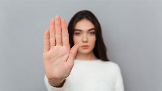 Das Bild zeigt eine Frau, welche mit einer flachen Hand "Stopp" signalisiert.