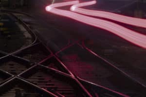 rote Leuchtspuren eines vorbeifahrenden Zuges und Schienen