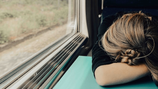 Das Bild zeigt eine schlafende Frau im Zug.