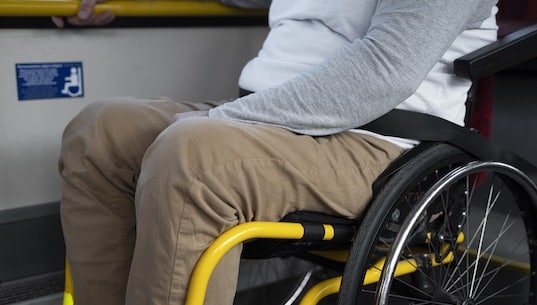 Das Bild zeigt einen Mann im Rollstuhl, welcher mit dem Zug reist.