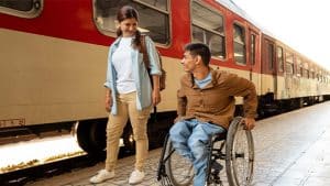 Das Bild zeigt einen Mann im Rollstuhl und einer Frau.