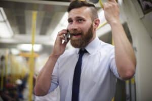 Das Bild zeigt einen Mann mit Hemd und Krawatte, der im Zug telefoniert.